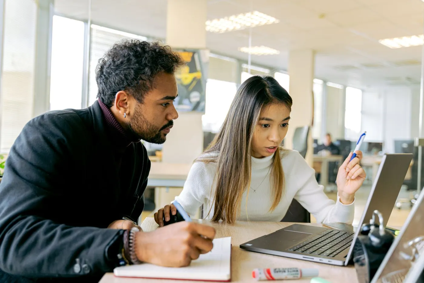 Een man en een vrouw in een kantooroverleg aan een laptop. Stockfoto, geen opdrachtgever van Arbopartner Brabant.